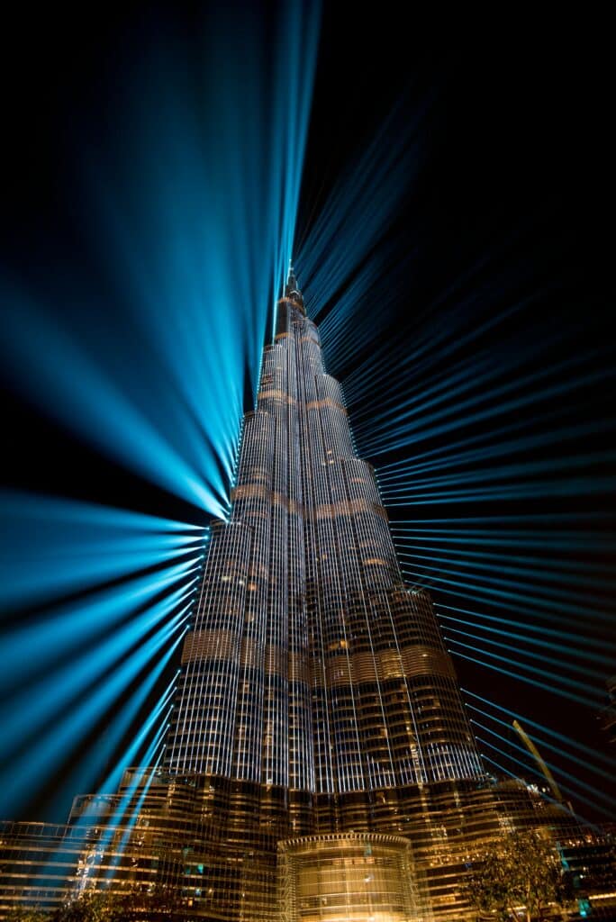 Visão de baixo para cima do maior arranha-céu do mundo para ilustrar o post de chip de celular para os Emirados Árabes. O prédio projeta luzes azuladas ao redor.- Foto: Thomas Drouault via Unsplash