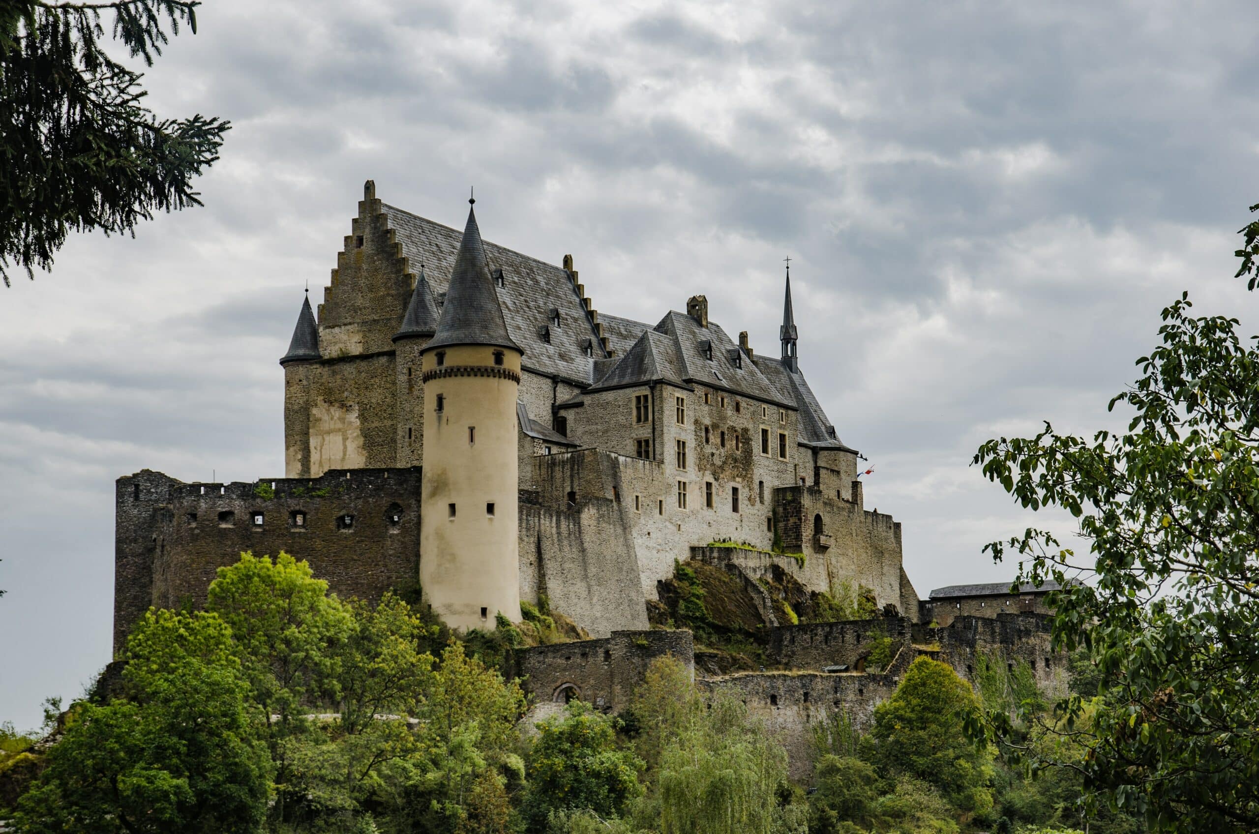 Vista do Castelo de Vianden, Luxemburgo que foi construído em estilo românico dos séculos XI a XIV cem volta de árvores.