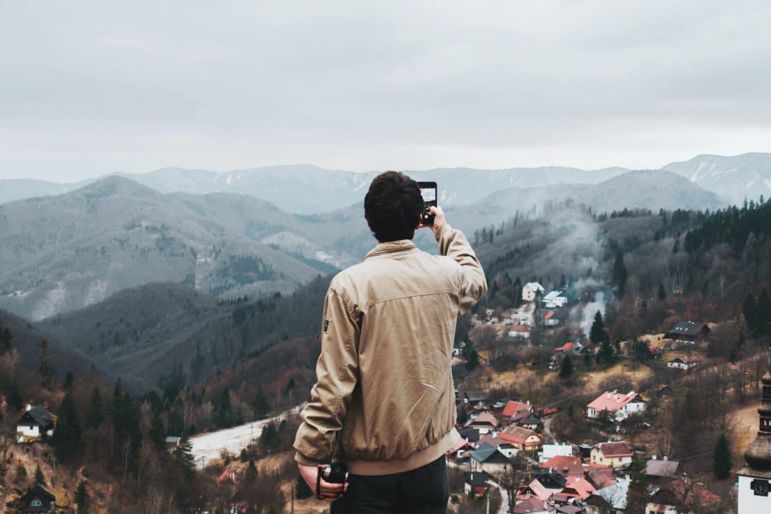 Homem em cima de um monte tirando foto de cima da cidade abaixo, em Espanha Dolina, Eslováquia -Representa chip celular Eslováquia