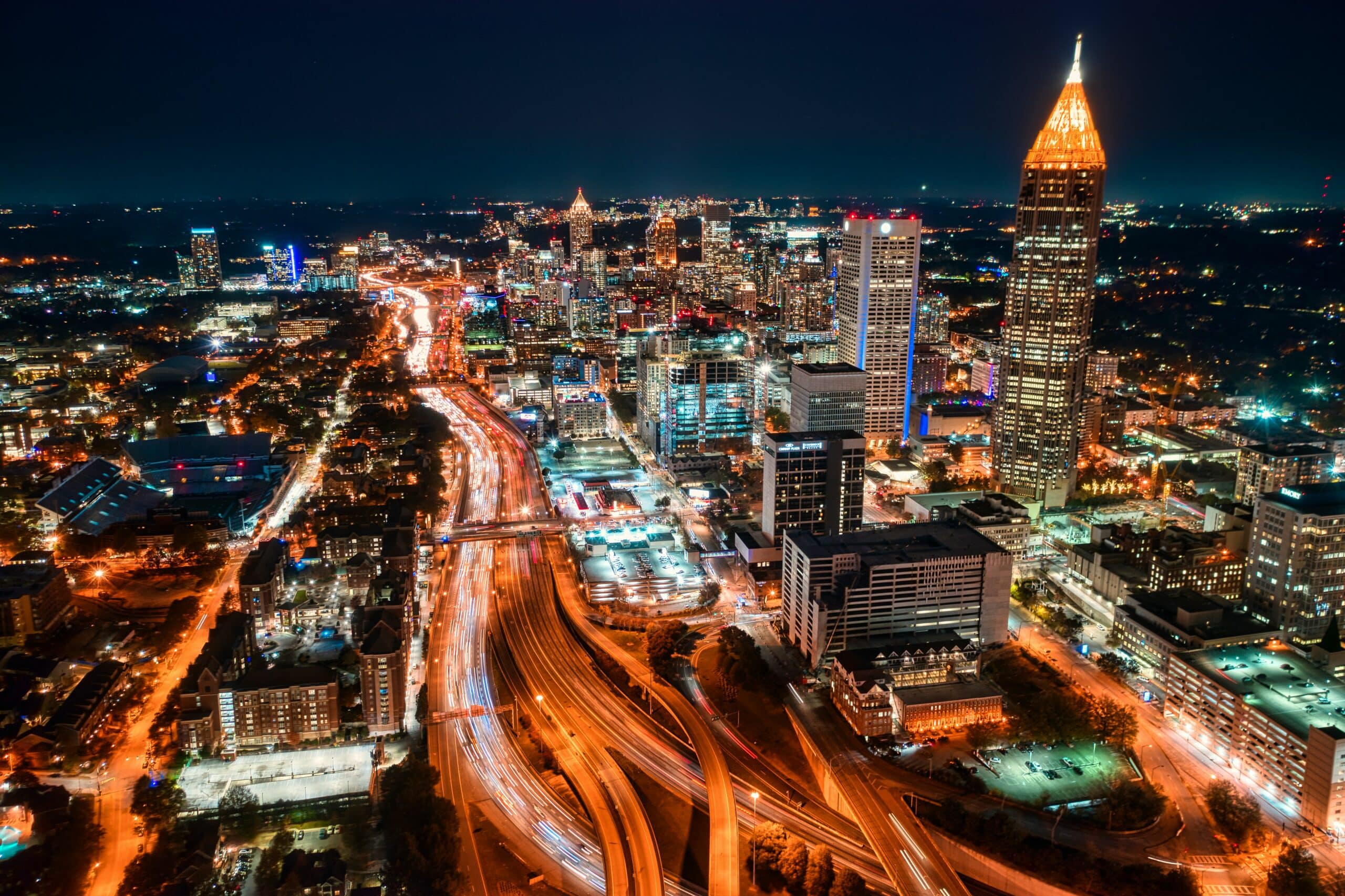 Centro de Atlanta à noite com prédios altos iluminados e ruas com curvas em volta.
