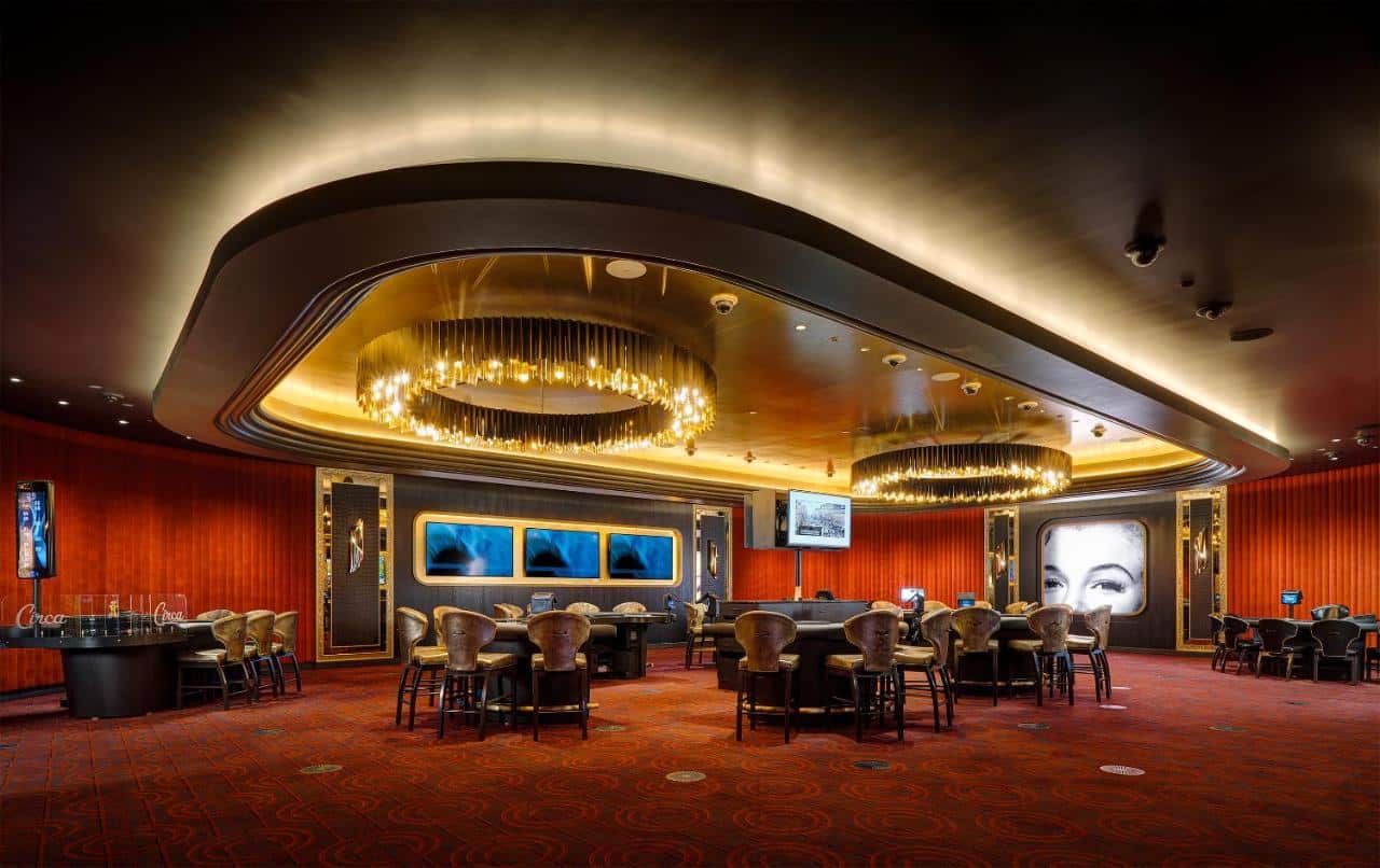 Área de entretenimento do Circa Resort & Casino - Adults Only com máquinas de casino, carpete vermelho, lugares para se sentar e lustres redondos