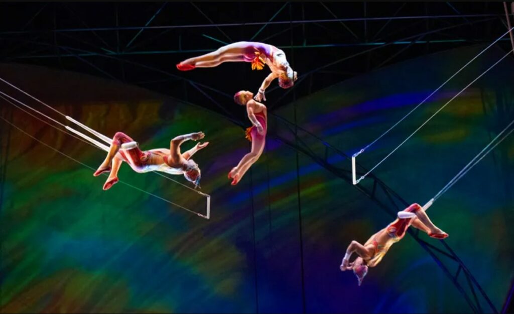 Quatro acrobatas pulando entre suportes no teto do espetáculo "Mysterè". - Foto: Divulgação oficial via site