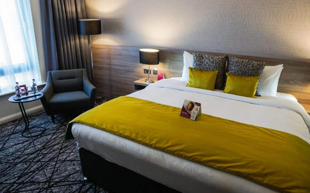 Quarto do Crowne Plaza, um dos hotéis em Liverpool, com cama de casal, abajur na escrivaninha ao lado e poltrona com mesinha redonda pequena
