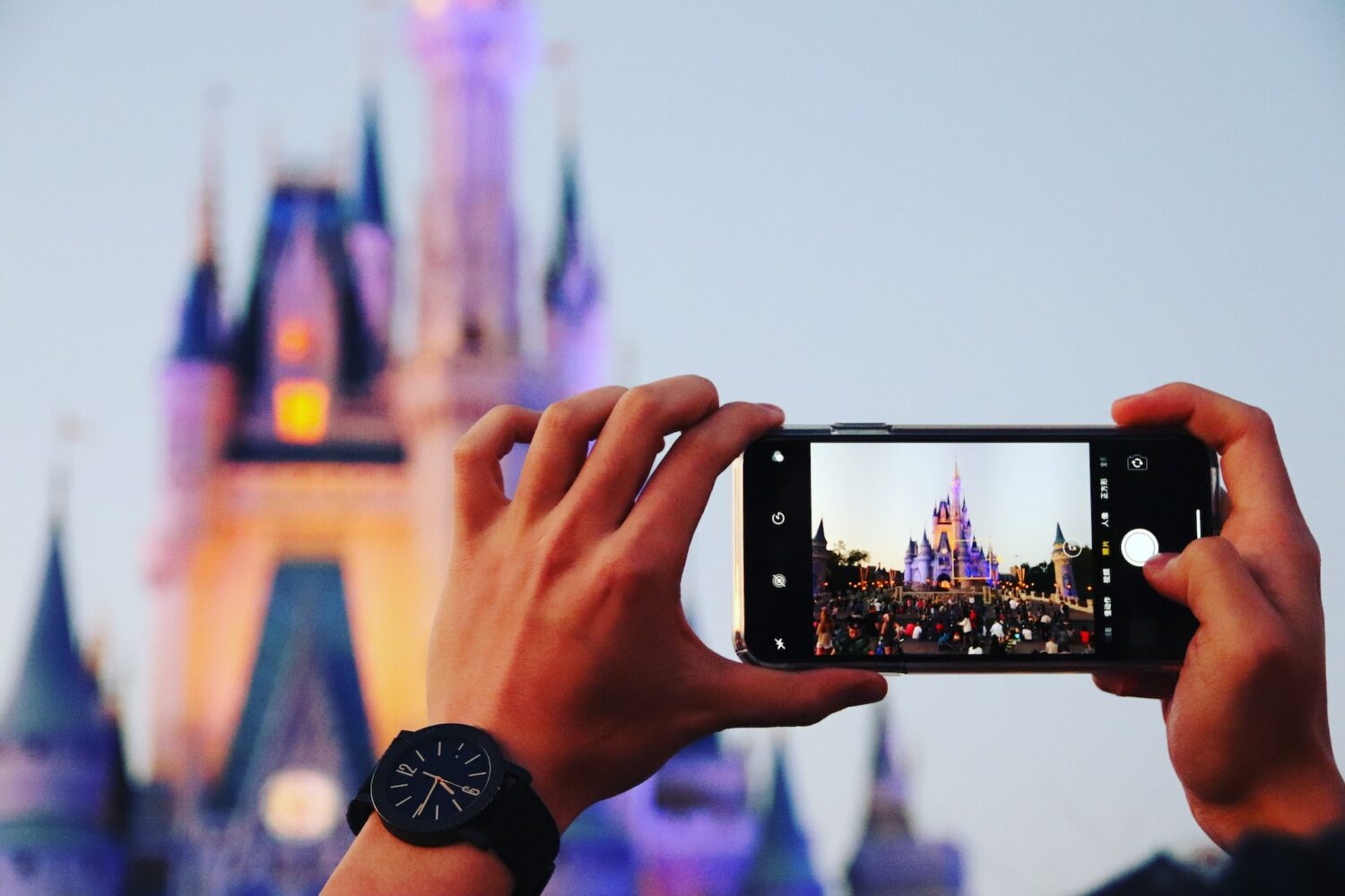 Uma pessoa segurando um celular e fotografando o Magic Kingdom em Orlando