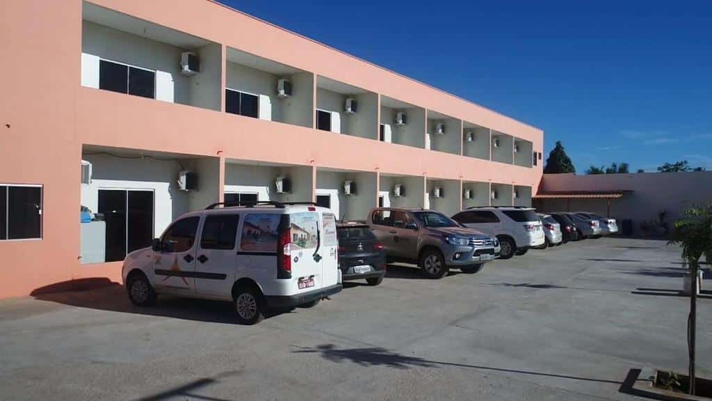 fachada alaranjada com carros na frente e diversas varandas dos quartos em dois andares com céu azul na Pousada Aerogrill, uma das pousadas em Juazeiro do Norte