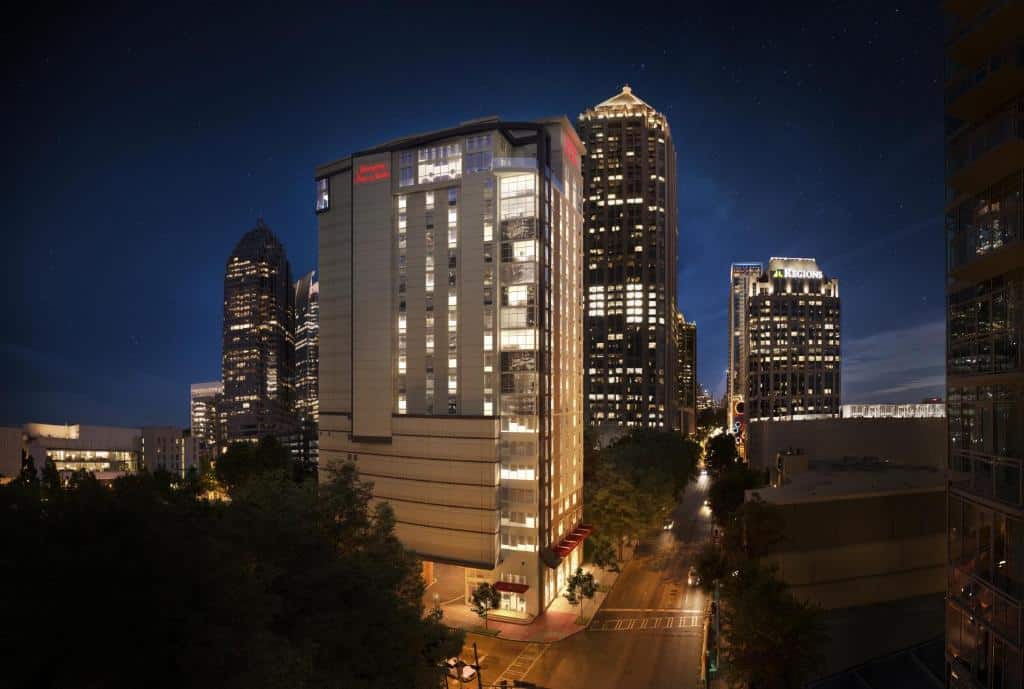 Vista da frente do Hampton Inn & Suites Atlanta-Midtown, Ga a noite com luzes nas acesas nas janelas do hotel.