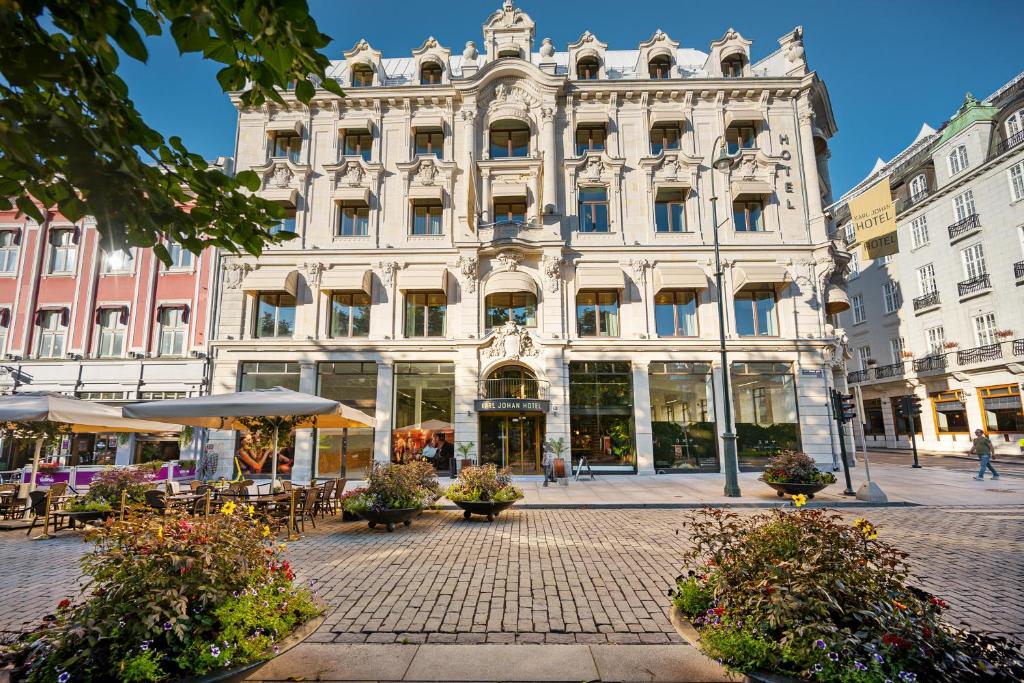 Frente do Karl Johan Hotel durante o dia com arquitetura europeia rustica, o prédio está com branca e possui várias janelas. Representa hotéis em Oslo.