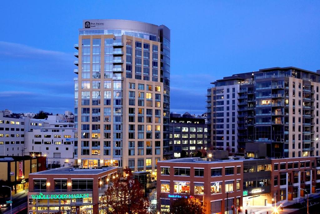Vista do prédio do Pan Pacific Seattle  com outros prédios altos no anoitecer.