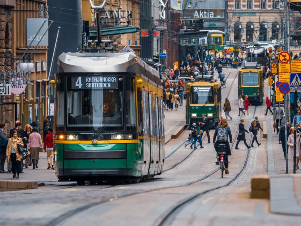 Bondinho verde e amarelo no meio da cidade, com pessoas caminhando e ciclistas ao redor para ilustrar o post de chip de celular para Finlândia. - Foto: Tapio Haaja via Unsplash