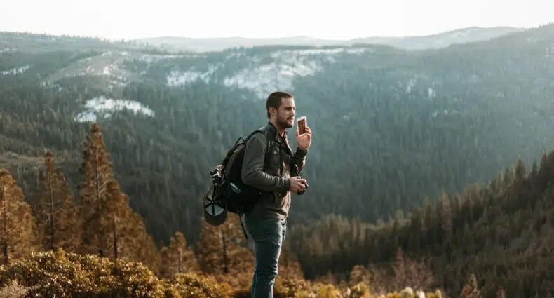 Homem com o celular próximo do ouvido num parque cheio de natureza em volta, na California