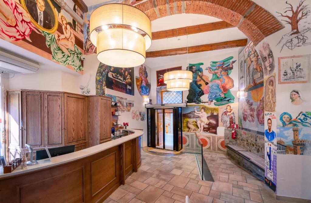 Recepção do Hostel Archi Rossi, com pinturas coloridas na parede, balcão de madeira e 2 lustres redondos suspensos no teto