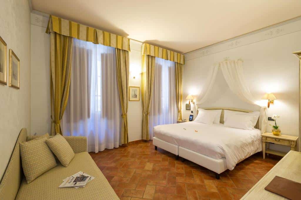 Quarto do Hotel Davanzati, com cama de casal (que pode virar duas de solteiro), duas janelas com cortinas que vão do teto ao chão e um sofá ao lado