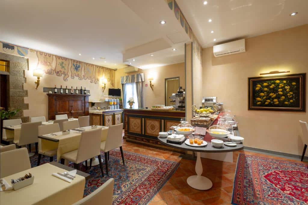 Área comum de alimentação do Hotel Davanzati, em Florença. com mesa de alimentos para o café da manhã, ar-condicionado e algumas mesas espalhadas com cadeiras