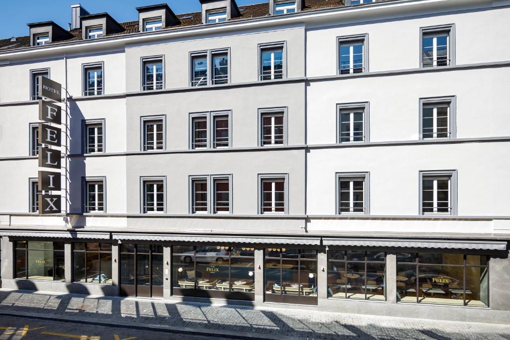Prédio cinza do Hotel Felix, em Zurique, com janelas, letreiro vertical escrito o nome do hotel e andar térreo todo de vidro mostrando as mesas e cadeira dentro do local
