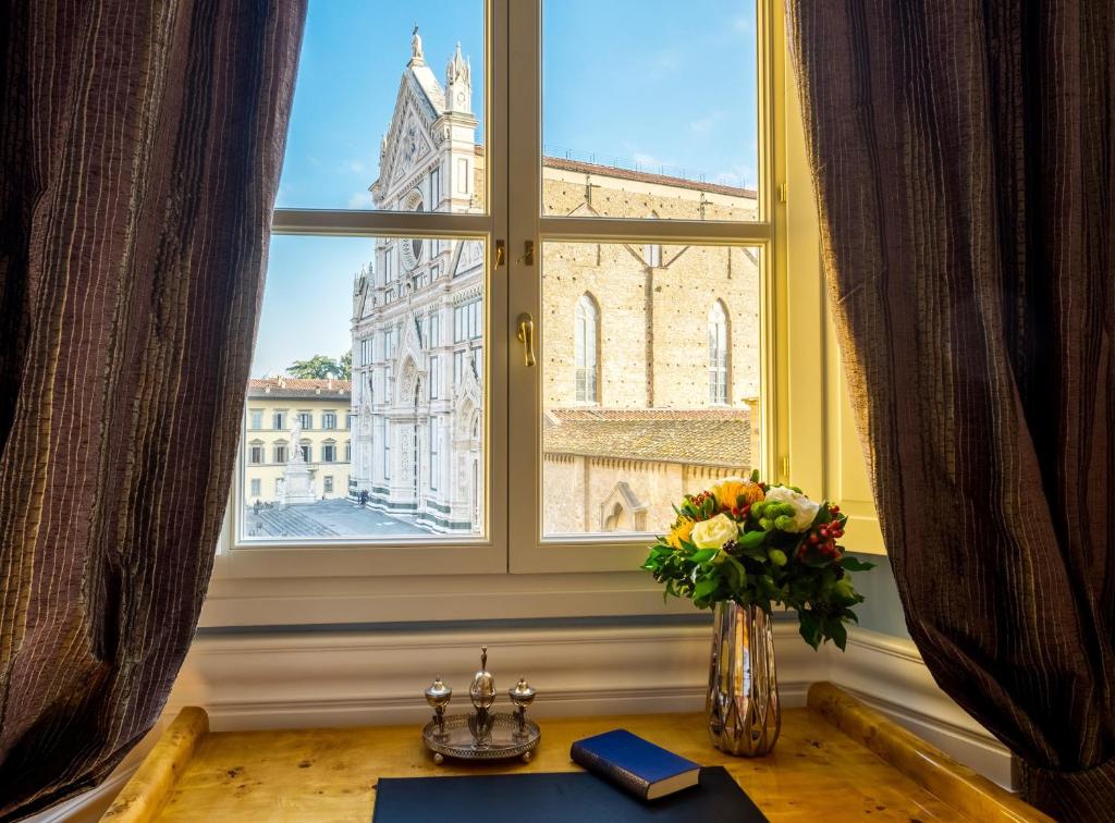 Mesa encostada em uma parede, com janela de vidro e vista para um prédio histórico localizado ao lado do La Maison du Sage, um dos hotéis em Florença