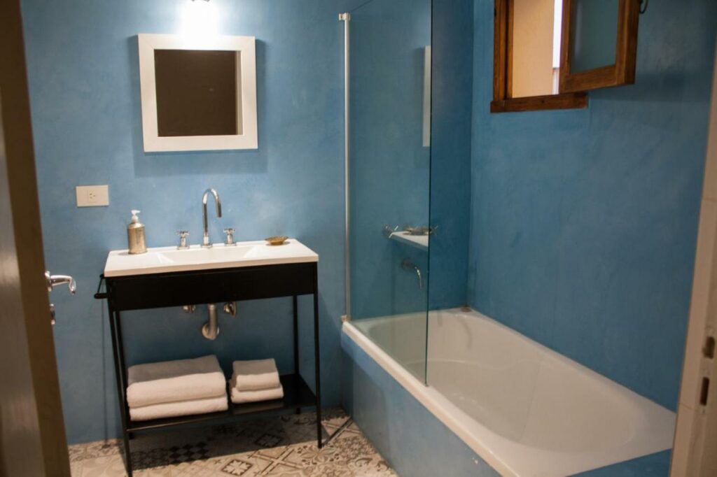 Banheiro do L'Adresse Hôtel Boutique com uma banheira, uma pia com toalhas disponíveis parte debaixo do móvel e um espelho
