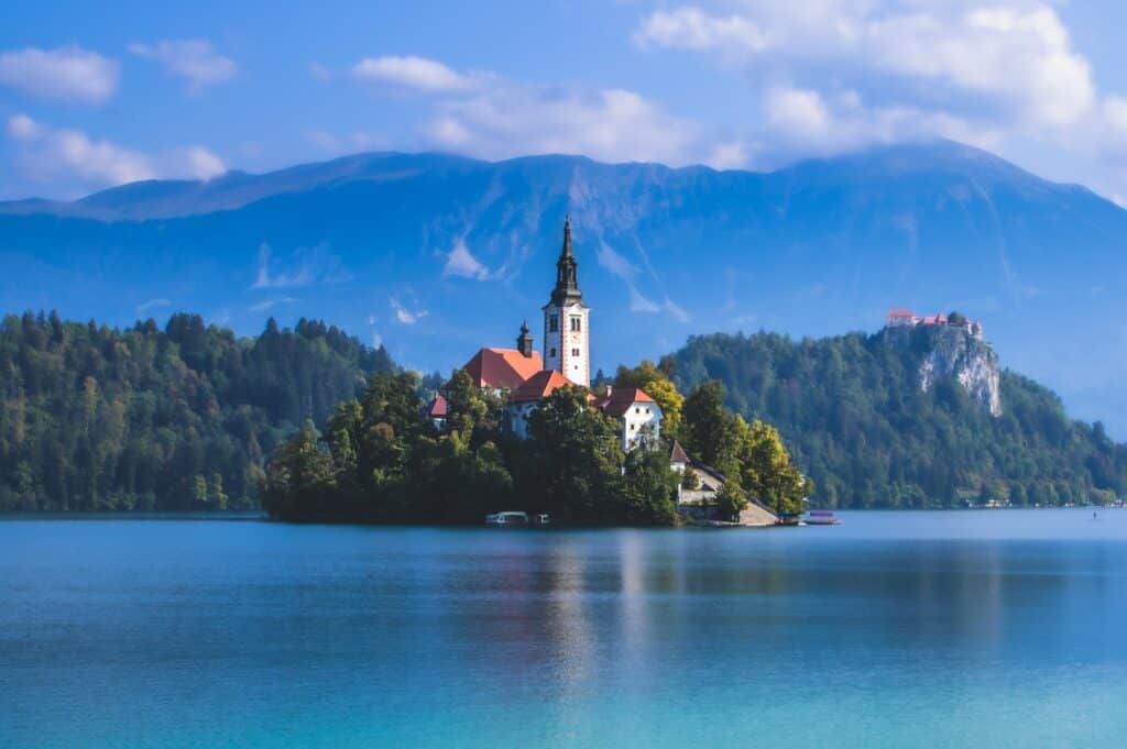 vista de uma ilha no Lago Bled com uma igreja bem ao centro e vegetação ao redor com céu azul e muitas nuvens, para ilustrar o post de chip celular Eslovênia
