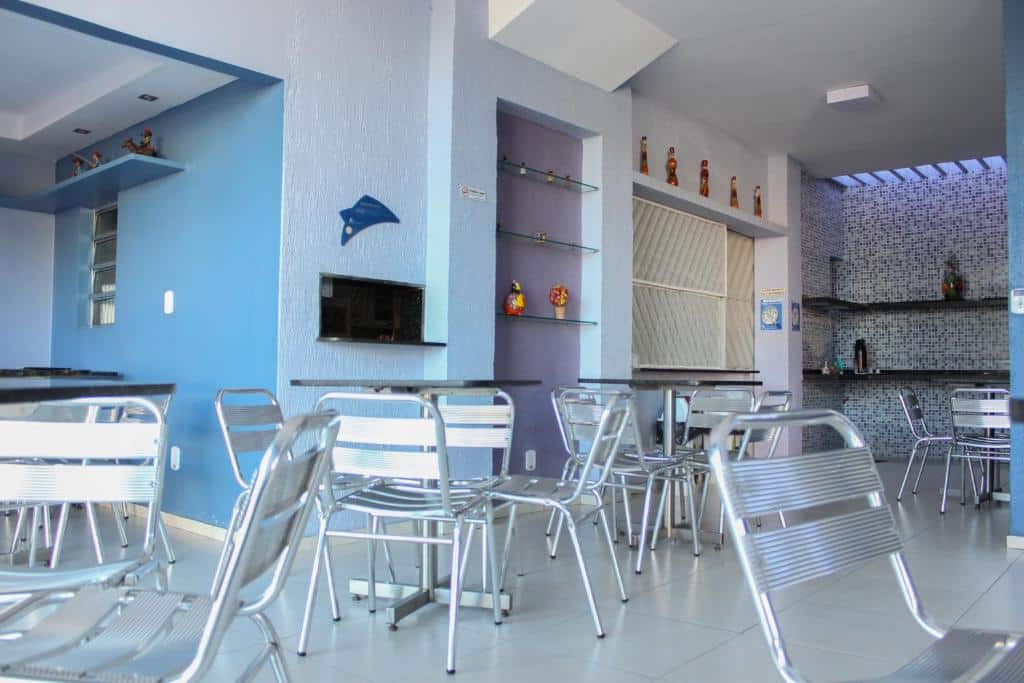 lounge com mesinhas e cadeiras, detalhes em azul e diversos enfeites em prateleiras na Pousada Planalto, uma das pousadas em Juazeiro do Norte