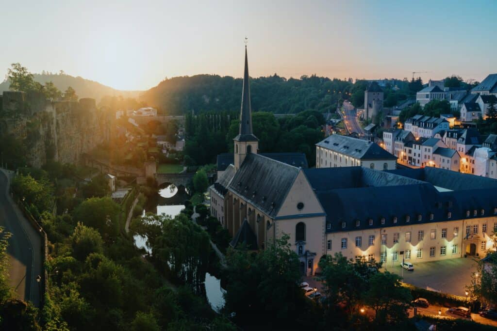 Vista de cima da Cidade de Luxemburgo, Luxemburgo com Igreja perto de um rio com uma ponte. Casas e árvores em volta no final de uma tarde. Representa chip celular Luxemburgo.