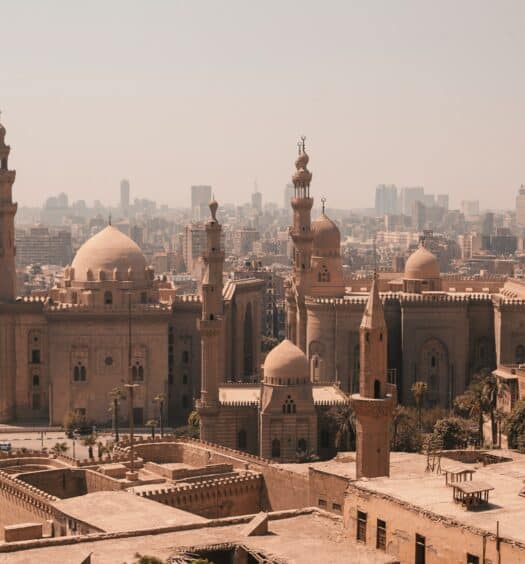 Foto de um templo mesquita bege, com a cidade do Cairo de fundo. - Foto: Omar Elsharawy via Unsplash