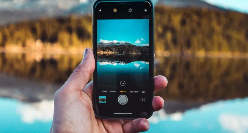 Celular na mão em frente ao rio em Whistler - Representa seguro viagem Whistler