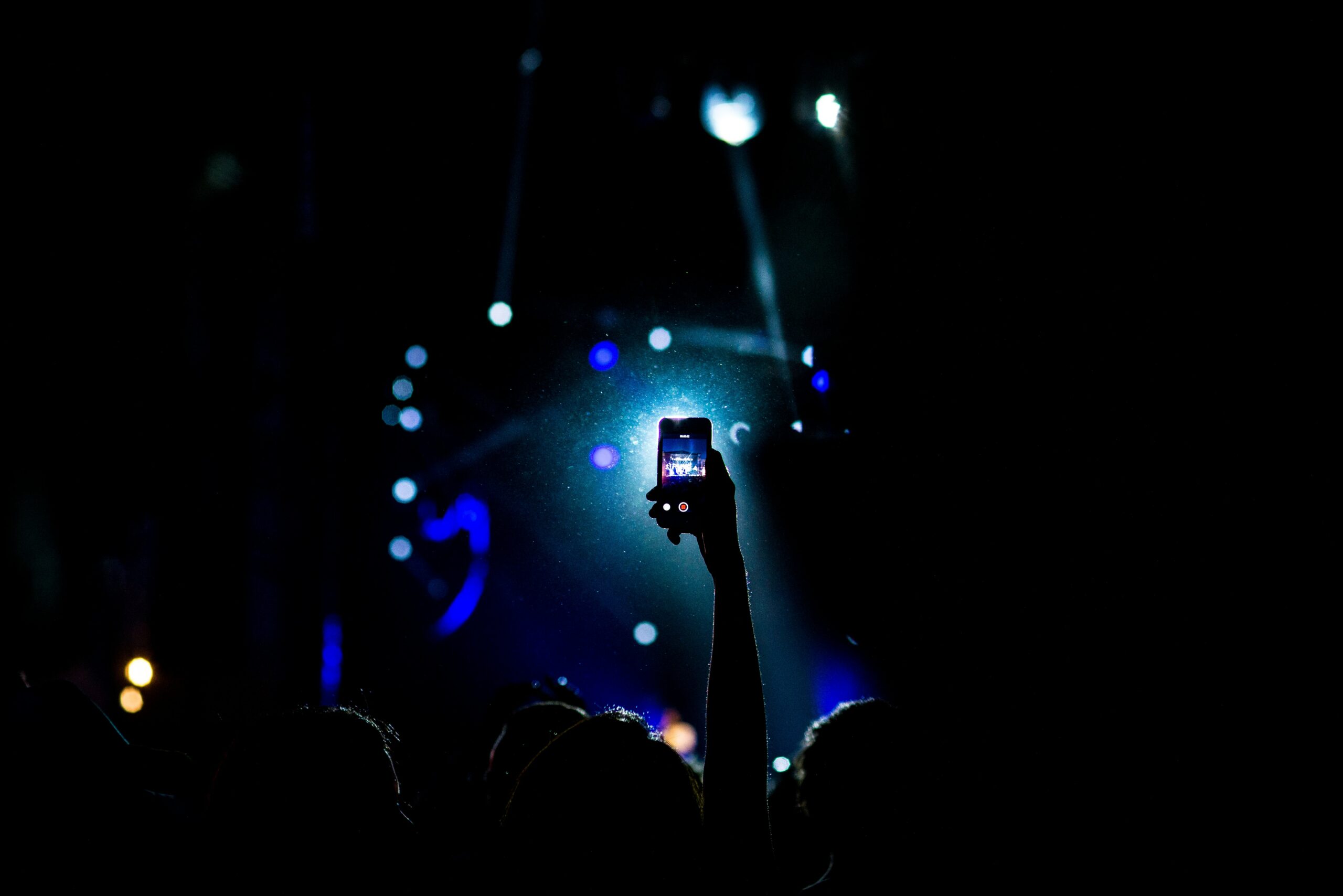 Celular na mão a noite tirando foto de um show. Representa chip celular México