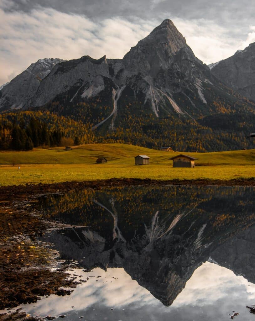 Montanha refletida em um lago com algumas cabanas na planície perto do lago para ilustrar o post de chip de celular para a Áustria. - Foto: Stefano Bernardo via Unsplash