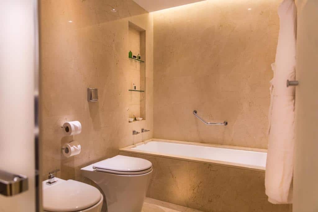 Banheiro no Palladio Hotel Buenos Aires - MGallery com uma banheira, uma barra de apoio, um vaso sanitário e alguns suportes para papel higiênico