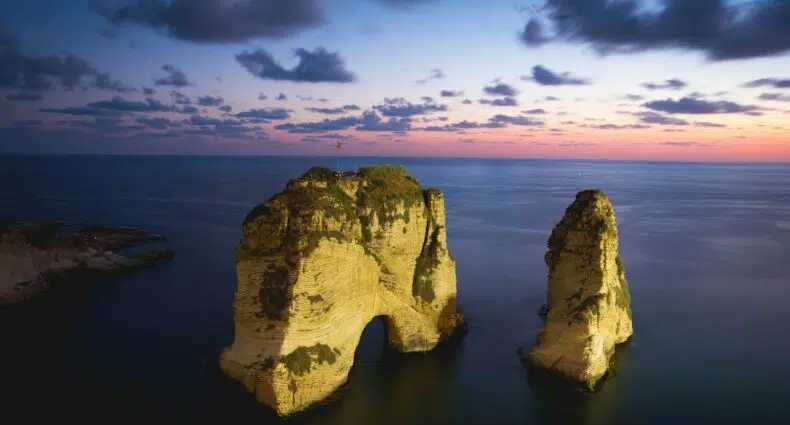 Vista aérea do ponto turístico Pigeon Rocks, céu com nuvens em tons de azul e rosa, ilustrando post seguro viagem Líbano