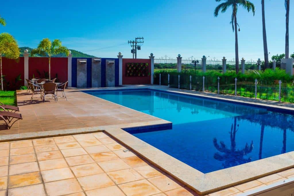 piscina retangular com parte mais rasa com mesa e cadeiras e céu azul no Hotel Encosta do Horto em Juazeiro do Norte