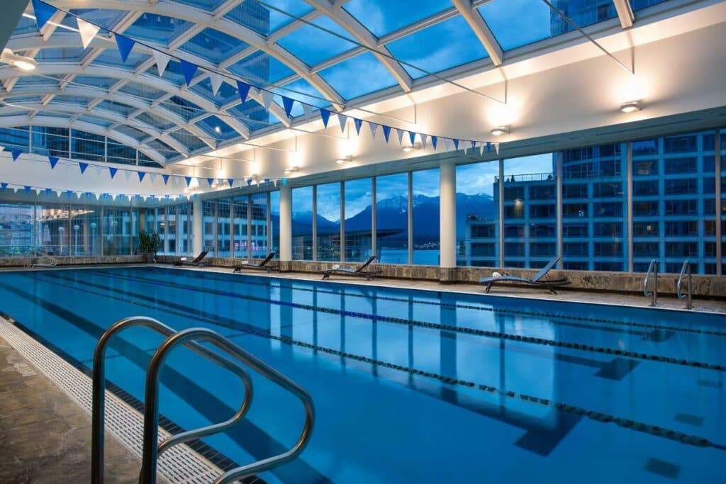 Piscina olímpica coberta no Auberge Vancouver Hotel, espaço muito amplo com teto e paredes de vidro