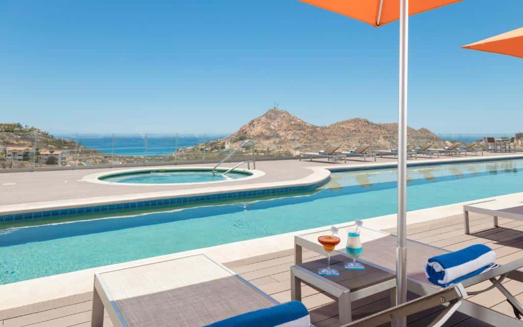 Vista da piscina Hampton Inn & Suites by Hilton Los Cabos com cadeira a beira da piscina.