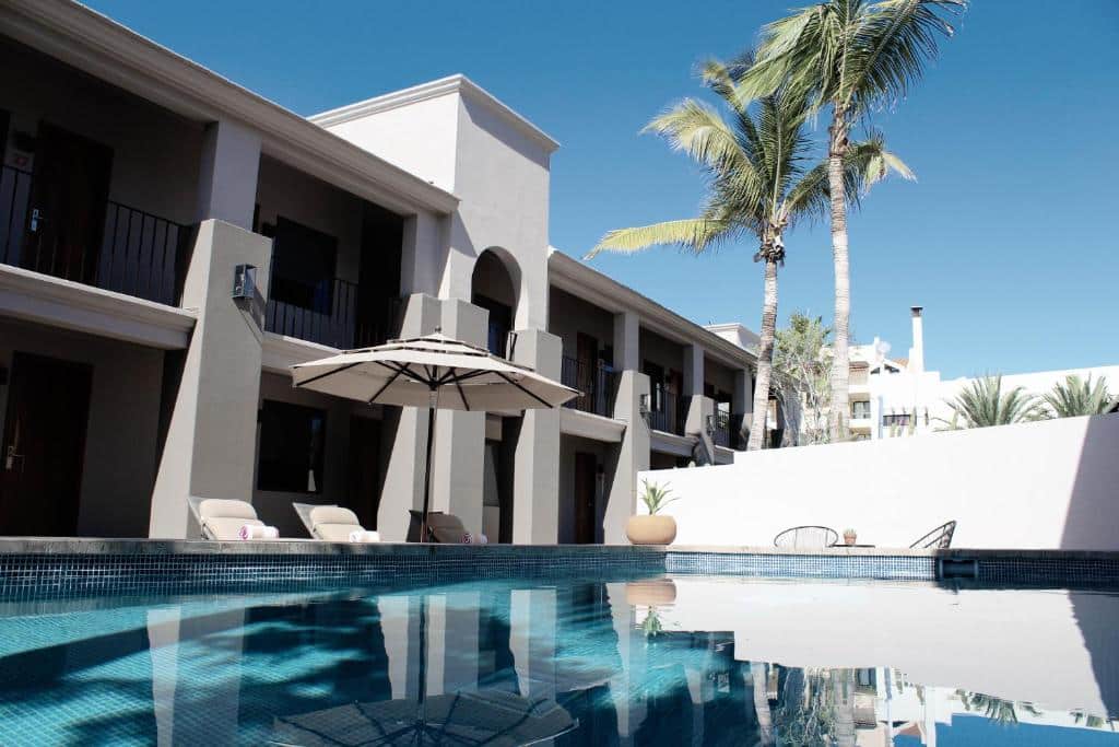 Piscina ampla do Six Two Four Urban Beach Hotel com cadeira do lado esquerdo e guarda-sol. Representa hotéis em Los Cabos.