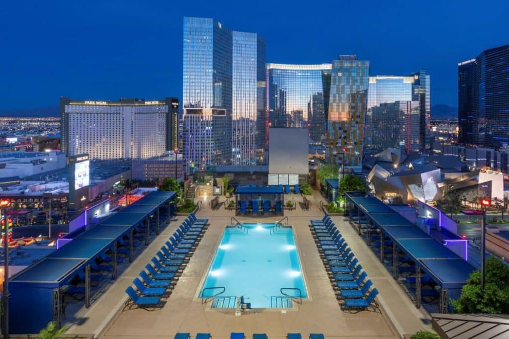 Ampla piscina do Polo Towers vista aérea com um deck ao redor da piscina com espreguiçadeiras azuis enfileiradas