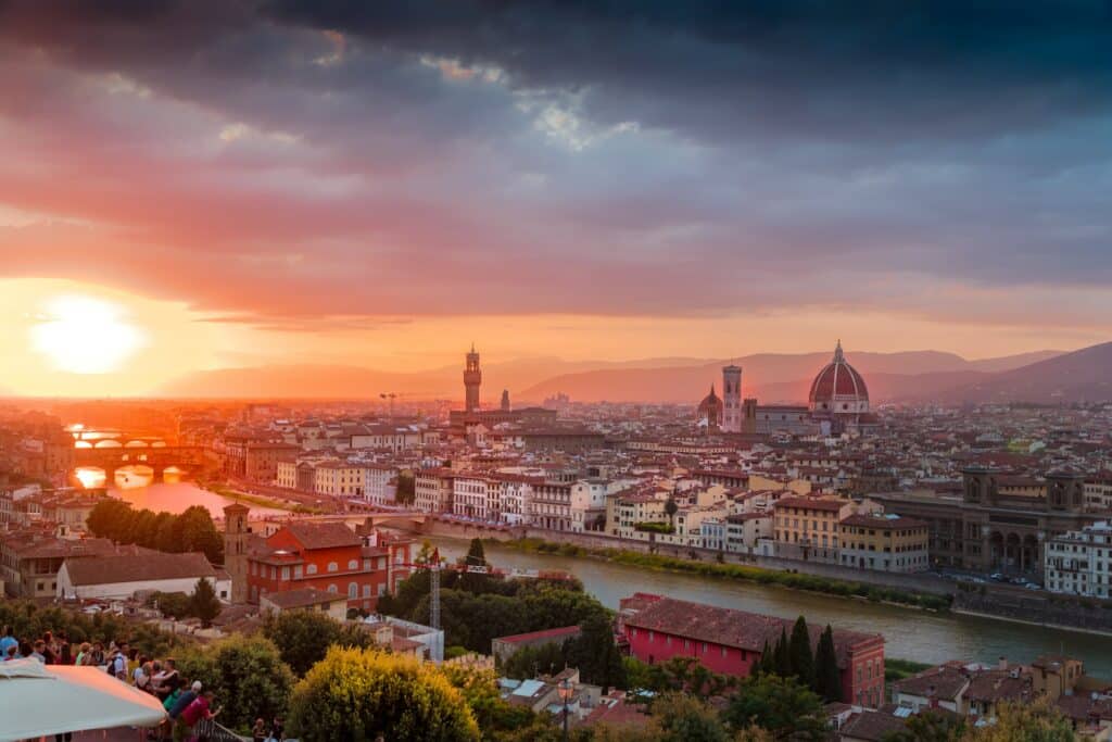 Pôr do sol alaranjado de Florença. com vista da cidade, incluindo o rio central, casas e árvores