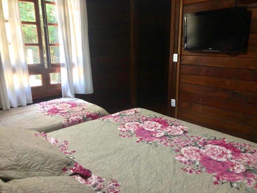 quarto com cama de casal e solteiro em frente à tv com janela na Chacara Papagaios em Mairiporã