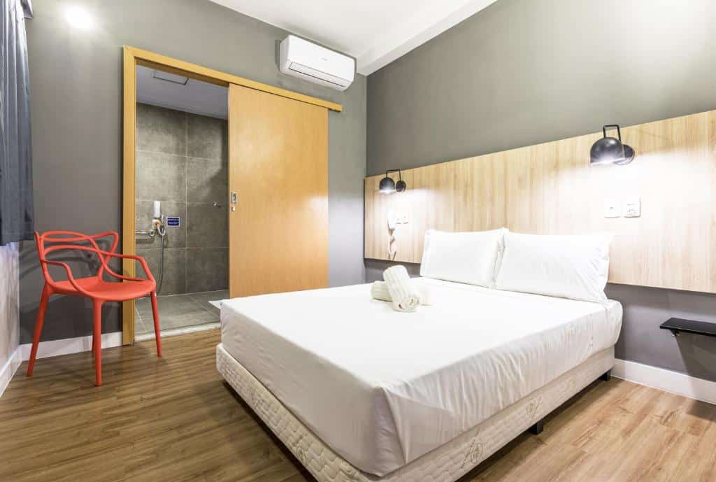 quarto com banheiro adaptado, cama de casal, poltrona e detalhes em madeira no Graal Inn Mairiporã