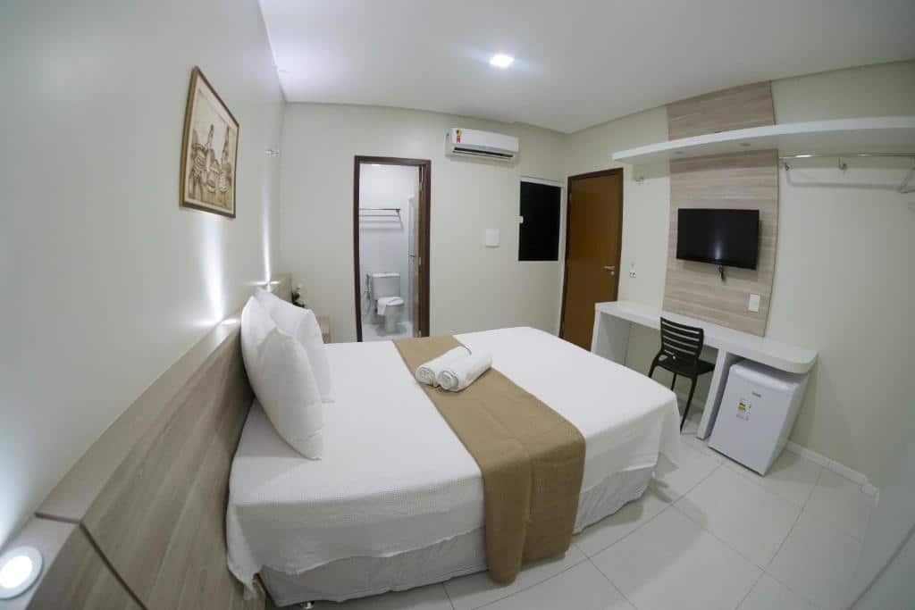 quarto com cama de casal, banheiro, tv e frigobar no Hotel Padre Cícero