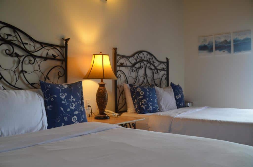 Quarto do Hotel Boutique Vista La Ribera com duas camas de solteiro e uma cômoda com luminária no meio das camas.