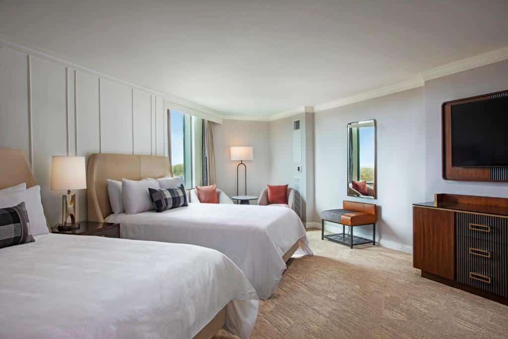 Quarto com duas camas, TV com rack em frente as camas e duas poltronas no lado esquerdo em hotéis em Atlanta.,