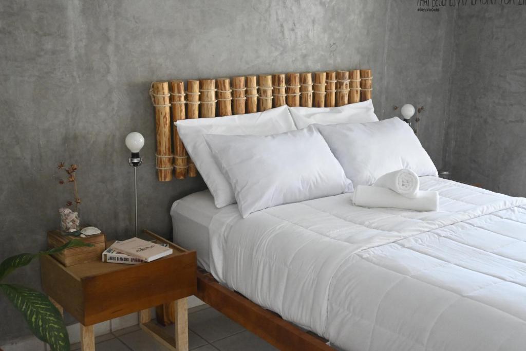 Quarto do Desert Heart Hostel com cama de casal, mesa de cabeceira, luminária com paredes cinzas. Representa hostéis em Los Cabos