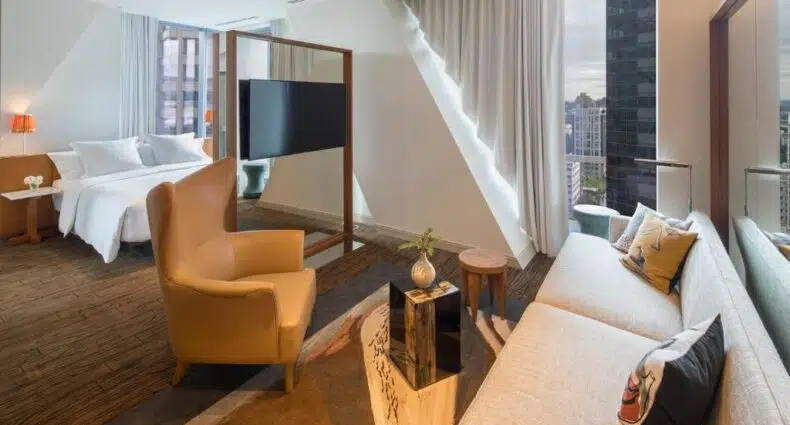 Vista do quarto do Lotte Hotel Seattle, com cama de casal com sala de estar e janelas panoramicas. Representa hotéis em Seattle