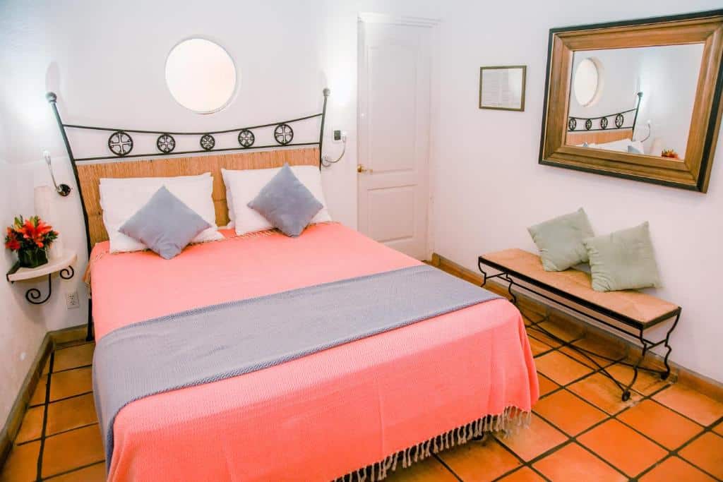 Quarto do Los Milagros Hotel com cama de casal, cômoda do lado direito, banco estofado do lado direito e espelho.