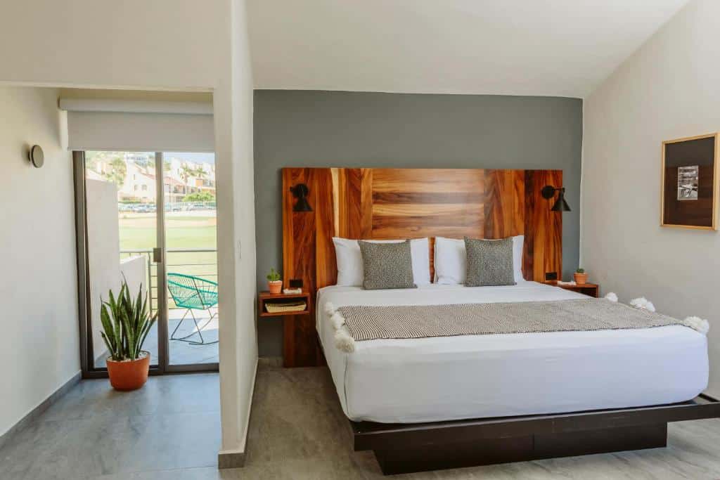 Quarto do Six Two Four Urban Beach Hotel com cama de casal ampla, cômodas ao lado da cama com luminárias e uma varada.