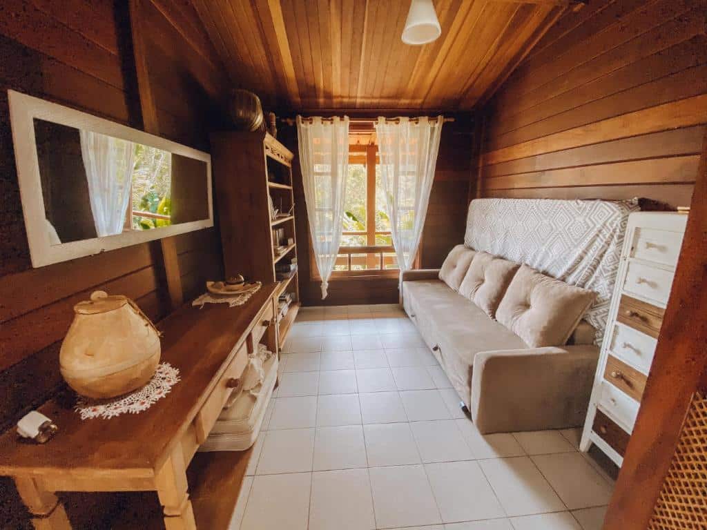 sala com sofá, móveis de madeira e janela com vista para o mar na Casa Ubatuba Vista para o Mar