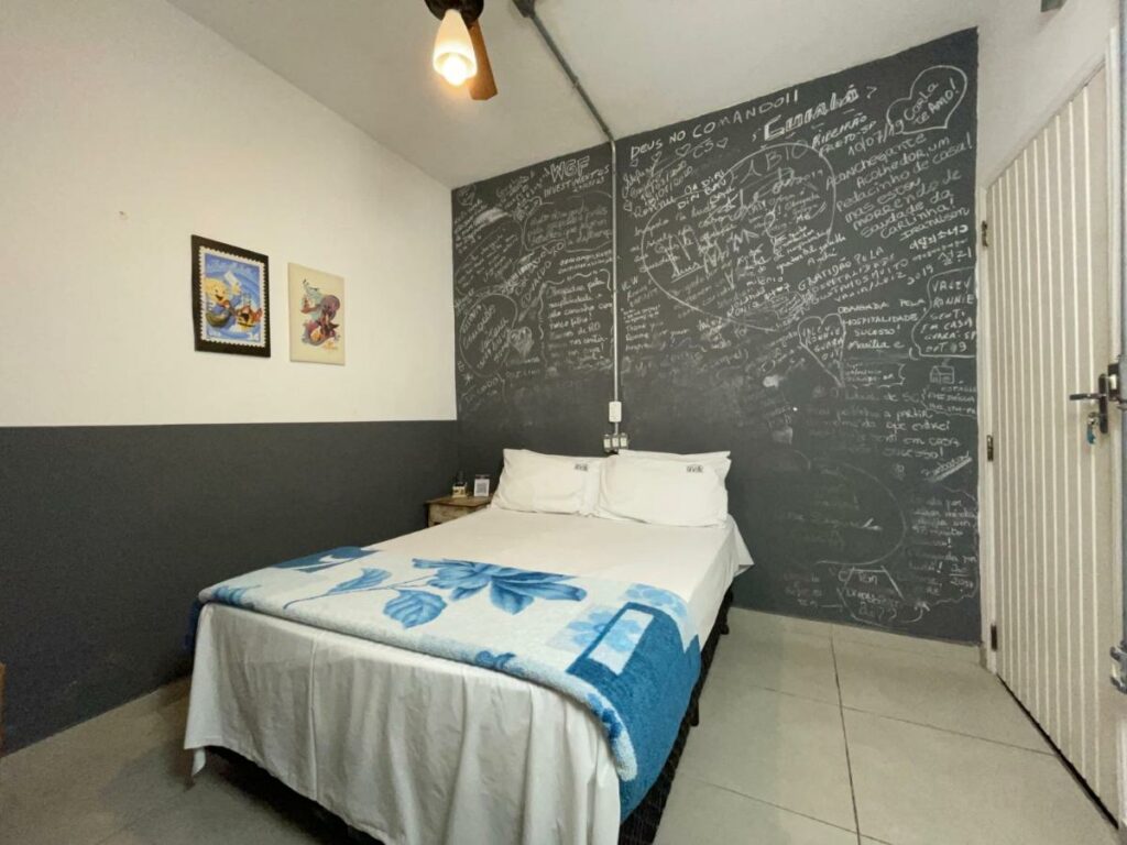 Quarto no Studio House com uma cama de casal, uma parede preta com desenhos feitos com giz, com um edredom e dois travesseiros na cama