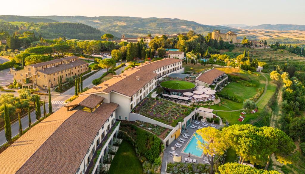 Vista aérea do Toscana Resort Castelfalfi, com bastante vegetação em volta, jardins, horta, piscina e prédios da acomodação
