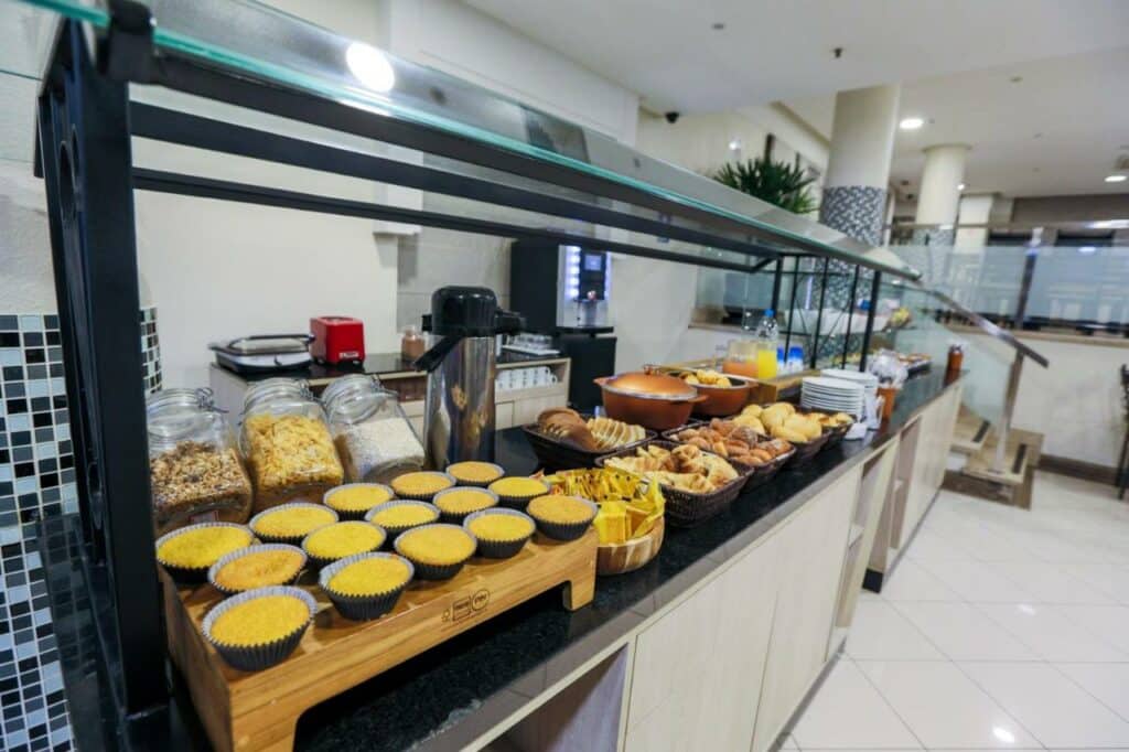 Área de café da manhã do Transamerica Executive Congonhas com bolos, pães e cafés