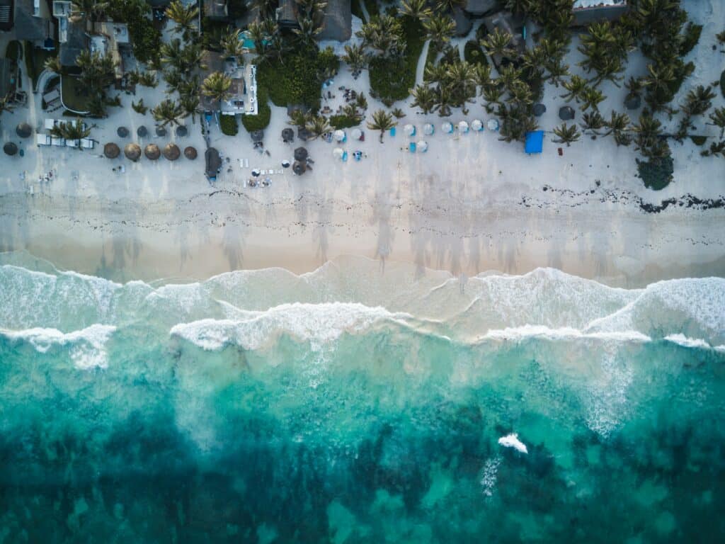 Vista de cima da praia de Tulum, México com areia branca na costa e mar azul turquesa.
