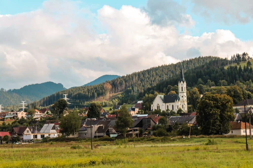 Vista da vila Černová, Ružomberok-Černová na Eslováquia com casas em volta, Igreja ao centro e uma floresta ao fundo com céus claro. Representa celular Eslováquia.